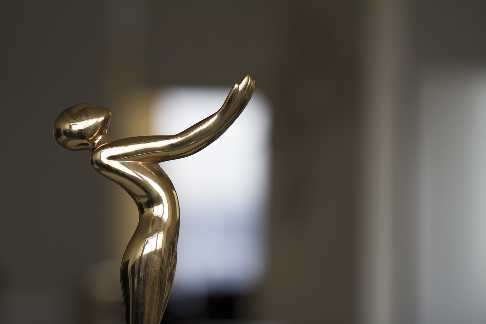 Yaron Yashinski's Promax trophy, a polished gold figure with arms swept back, photographed in the studio